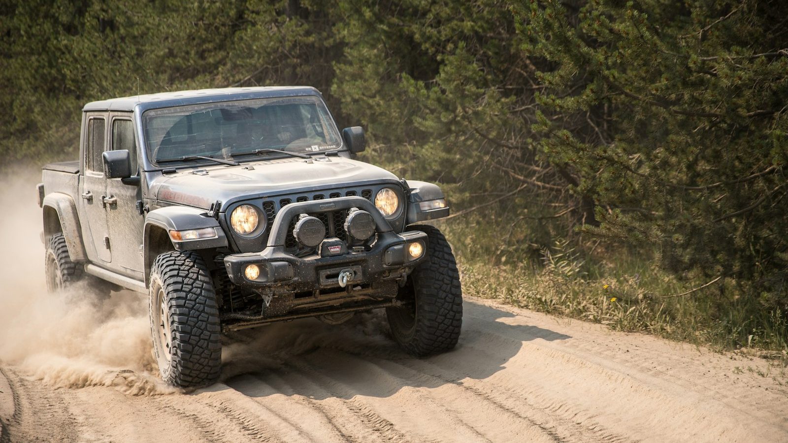 Jeep Gladiator kicking up dust on a dirt track