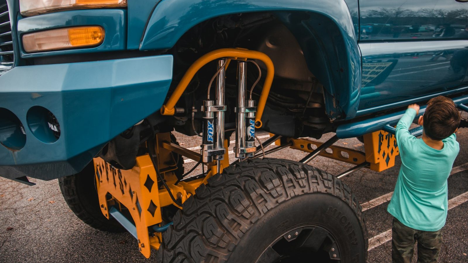Mechanic working on a lifted truck's front coilover suspension