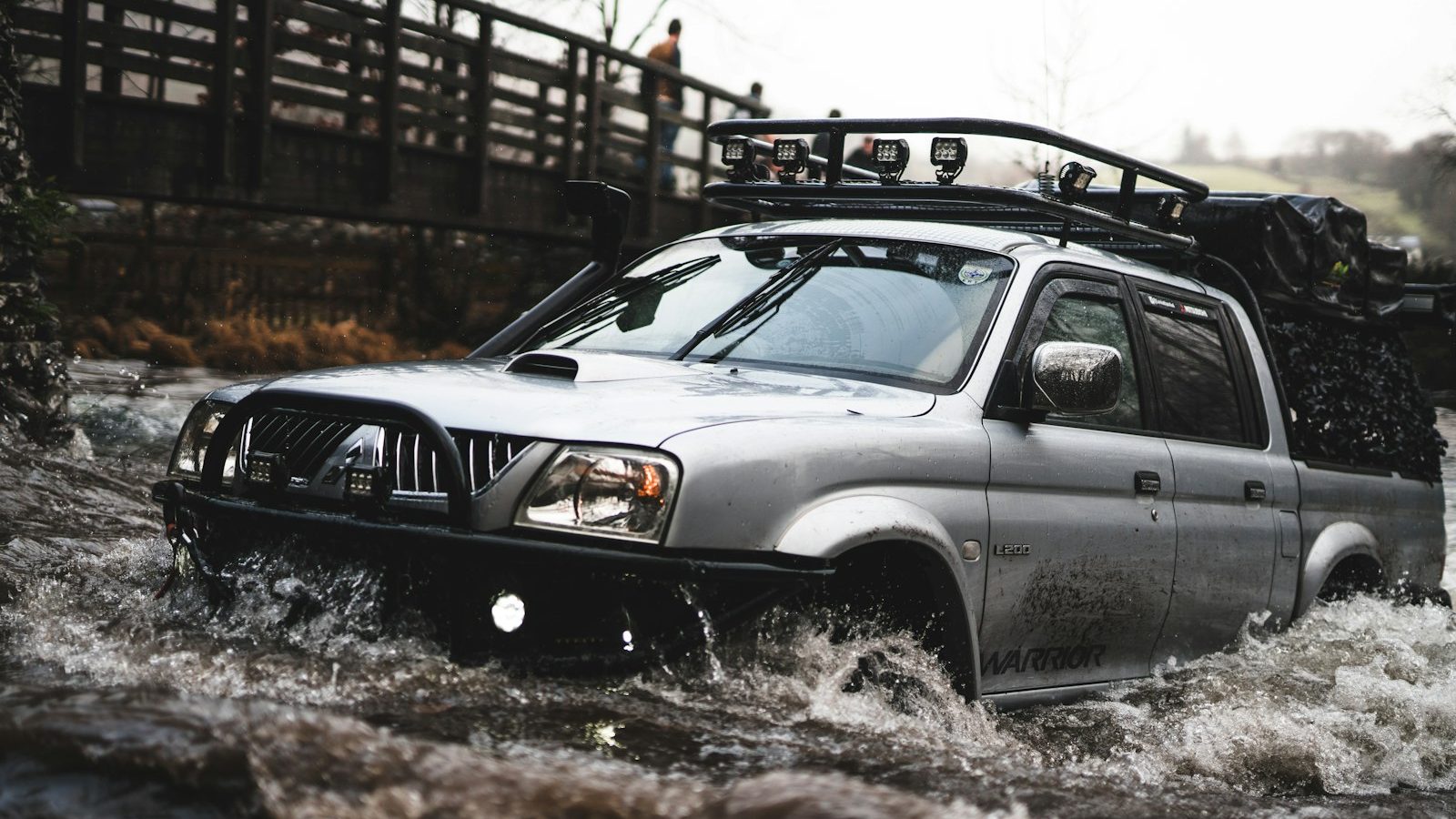 Pickup with a roof rack crossing a shallow river