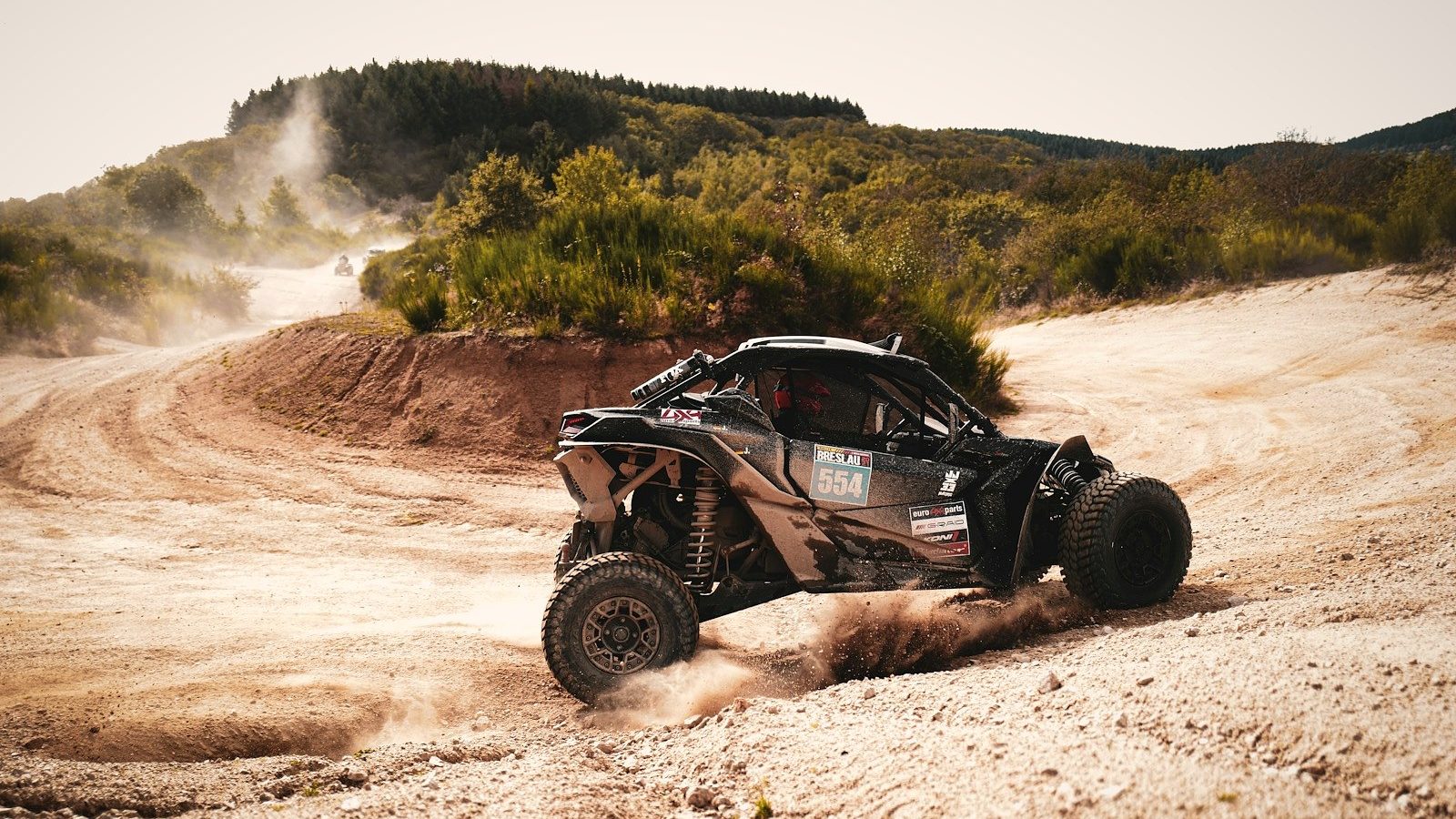 Can-Am Maverick X3 side-by-side sliding through a dirt corner and throwing roost