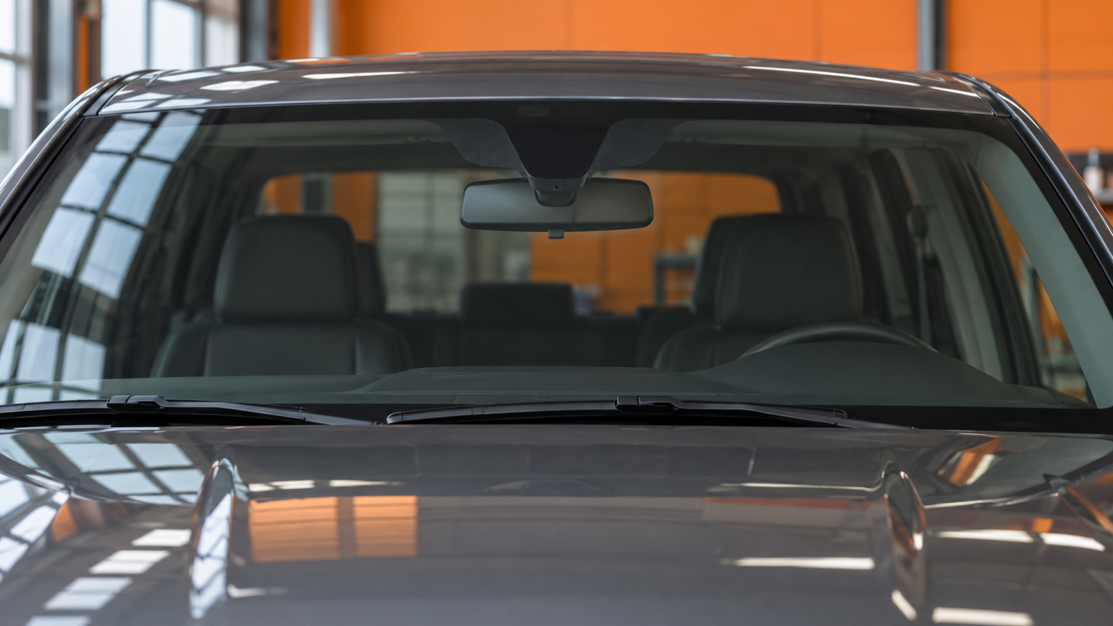 Windshield and rear-view mirror area of a parked pickup inside a workshop.